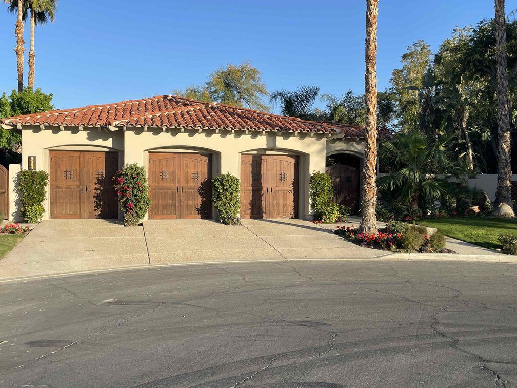 La Quinta investment residence with a red tile roof, wooden garage doors, and palm trees