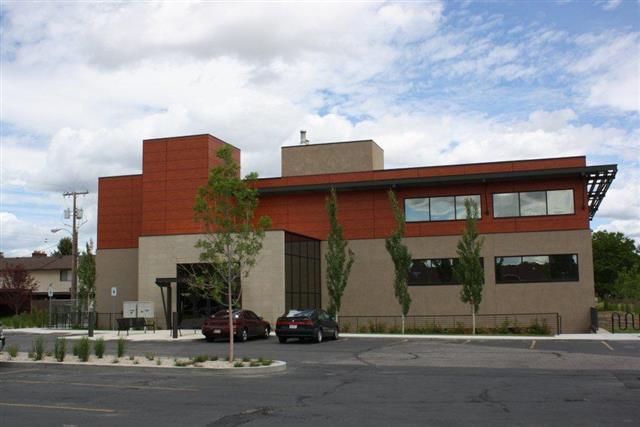 Renovated Billings office building with red upper frontage, large windows, and landscaped parking area
