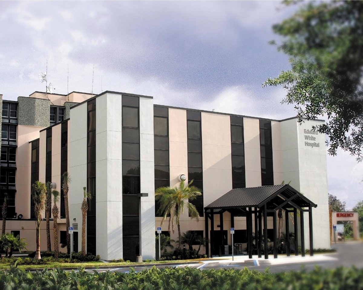 Exterior of the former Ed White Hospital, a six-story white building with a dark entrance canopy in St. Petersburg, Florida
